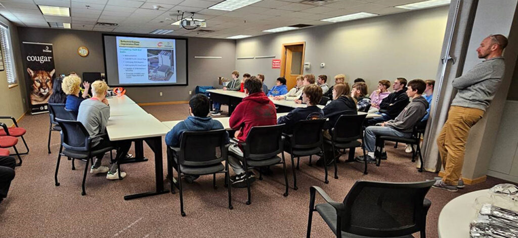 Engineer presents biomass-boiler slide to Wausau West students seated in Domtar Rothschild Mill conference room.